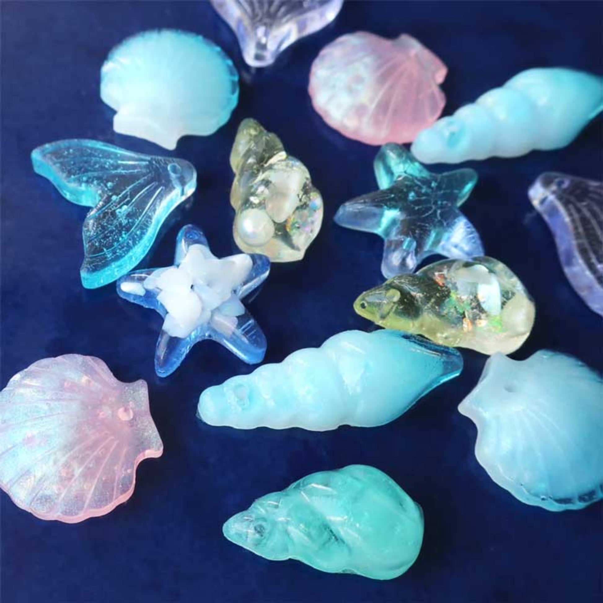 Finished resin jewelry pieces made using Onesika marine molds — starfish, shell, and fin charms in ocean tones.